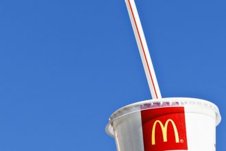 A McDonald's cup a plastic straw set against a blue sky