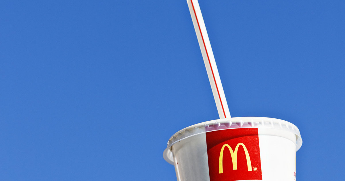 A McDonald's cup a plastic straw set against a blue sky