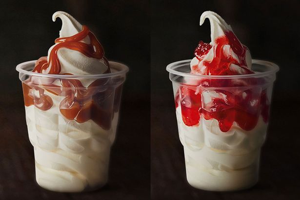 A caramel and strawberry McDonald's sundae sit side by side on a black background
