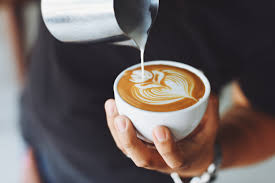 a barista pours milk into a cup of espresso coffee