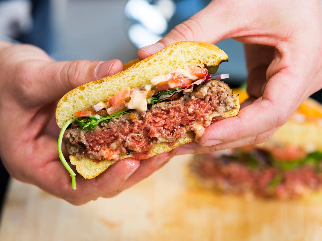 Impossible Meat burger 2.0 cut in half and held by two hands