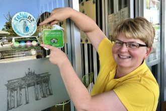 Lady pointing at cafe window with RefillNZ sticker