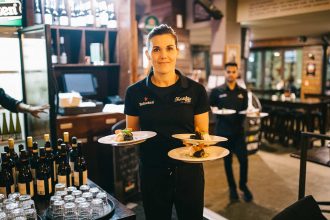 Female waiter looking at camera holding three plates of food