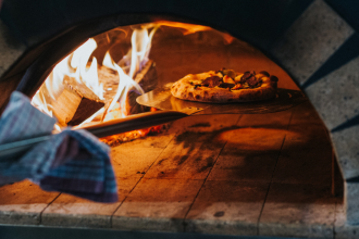 Pizza being cooked in hot stone stove