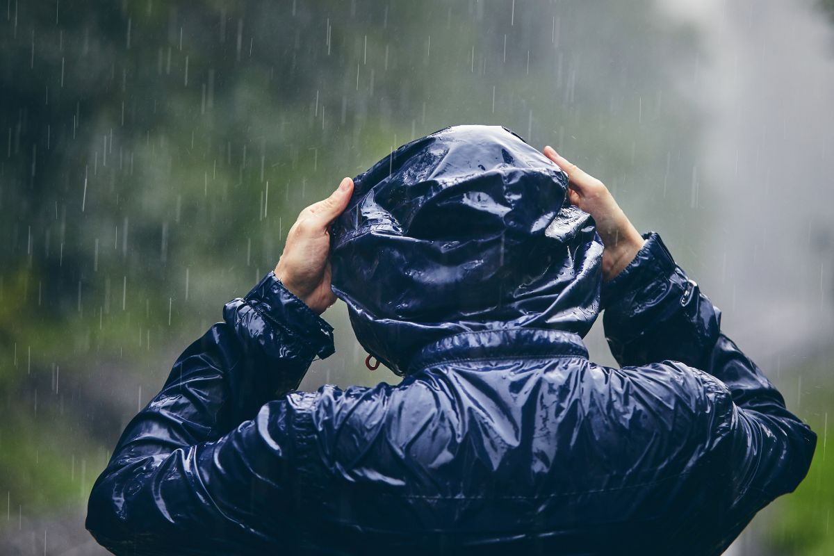 back of person putting hood on raincoat