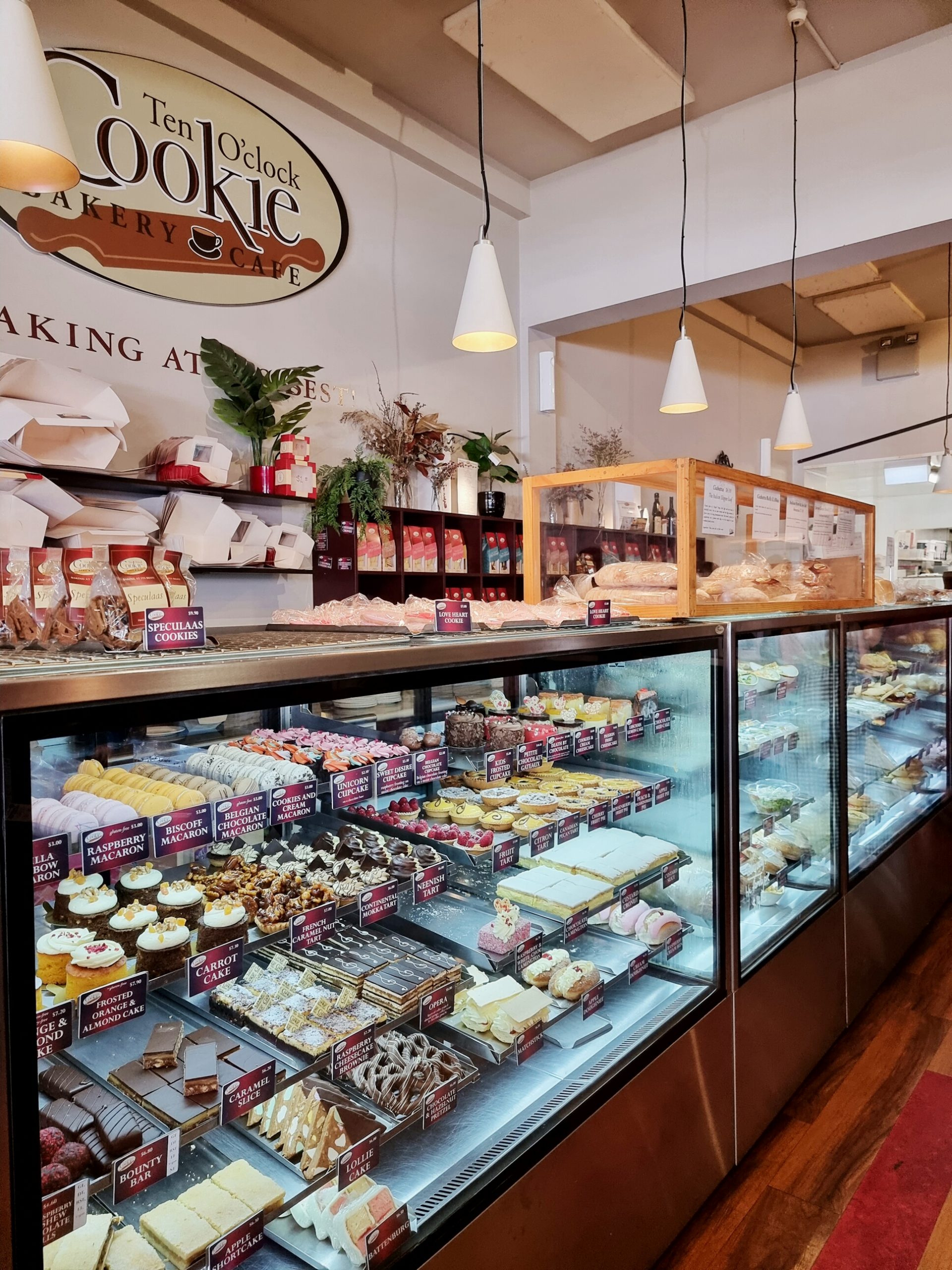 bakery cabinet view full of pastries and treats, lights hanging over, with bakery sign in view