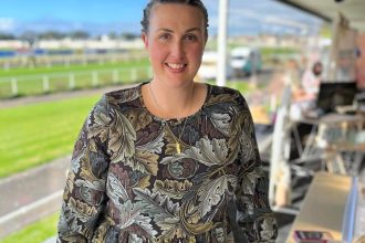 Rebecca Chubb woman owner of Little Liberty Creamery standing in cart smiling with field in background
