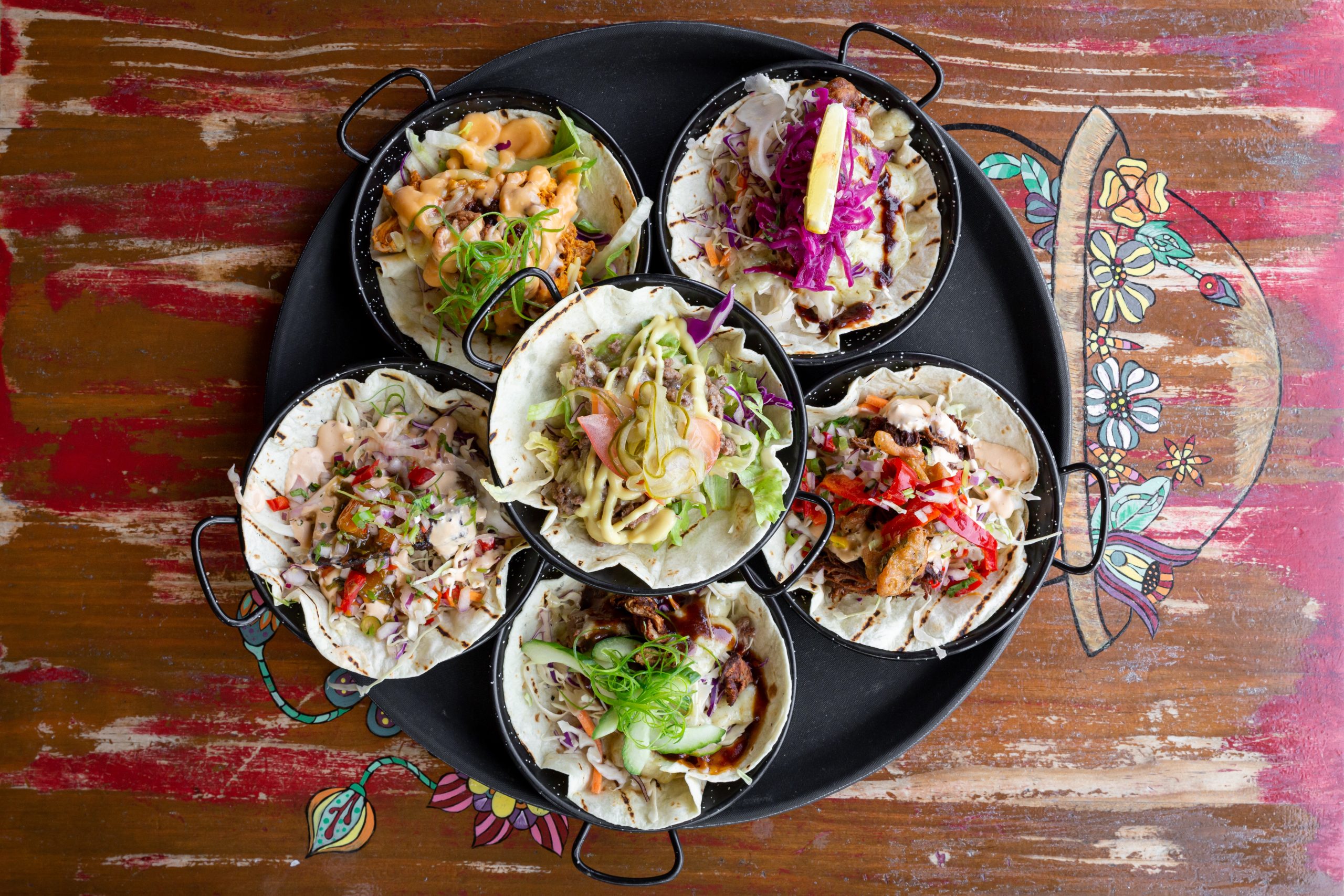 black plate of a selection of tacos on table