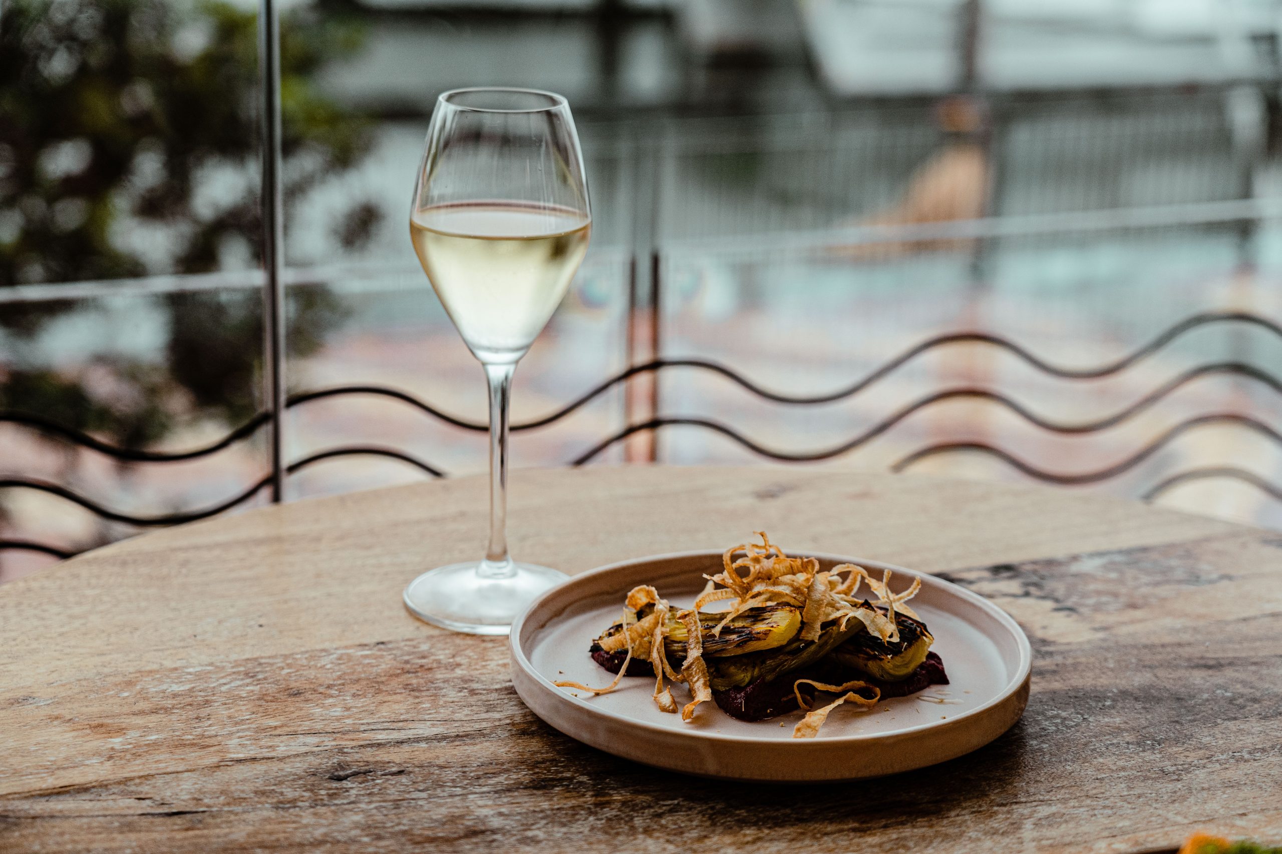 small plate of food on table accompanied with a glass of white wine