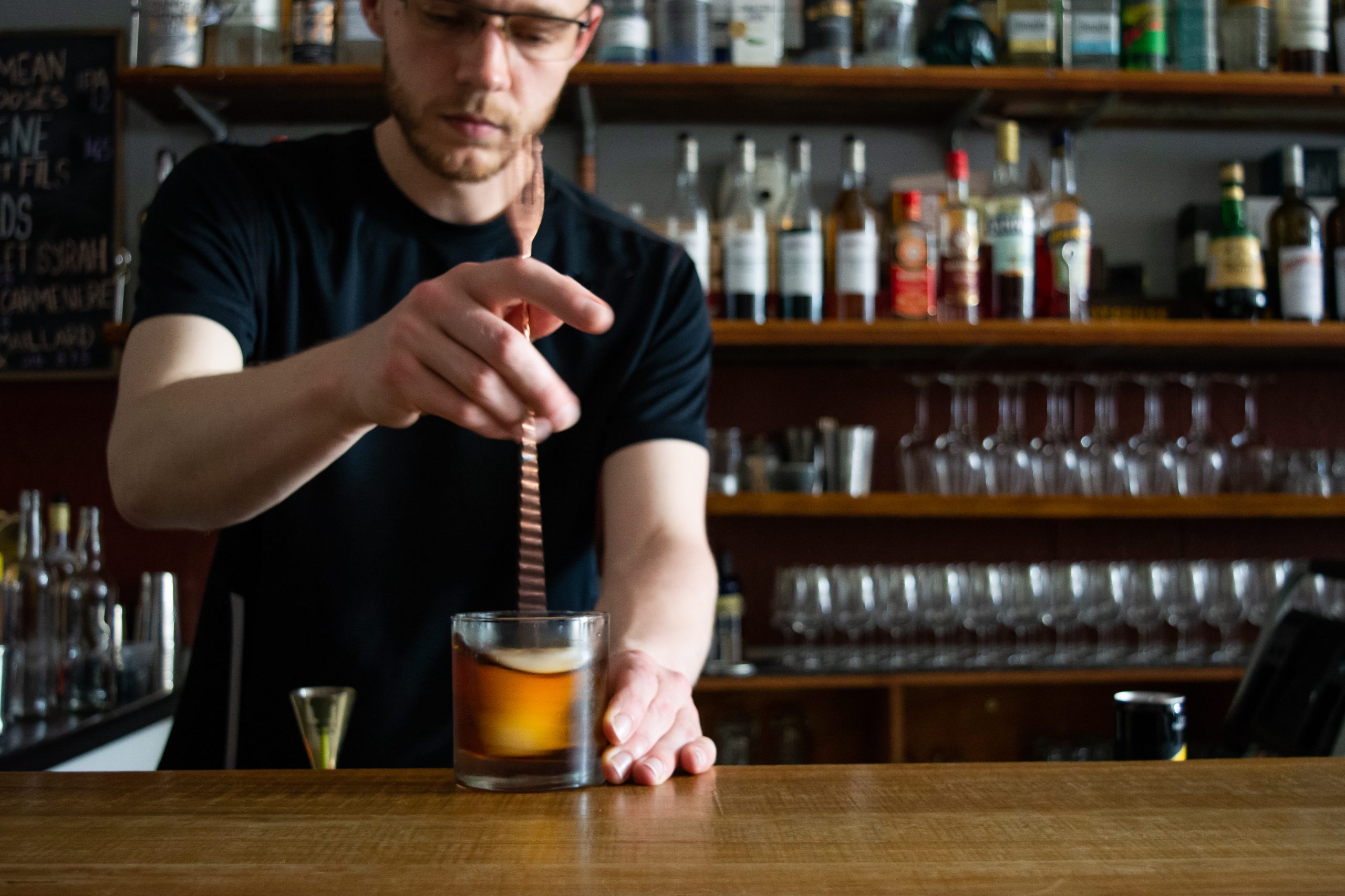Bartender at bar bench mixing a cocktail