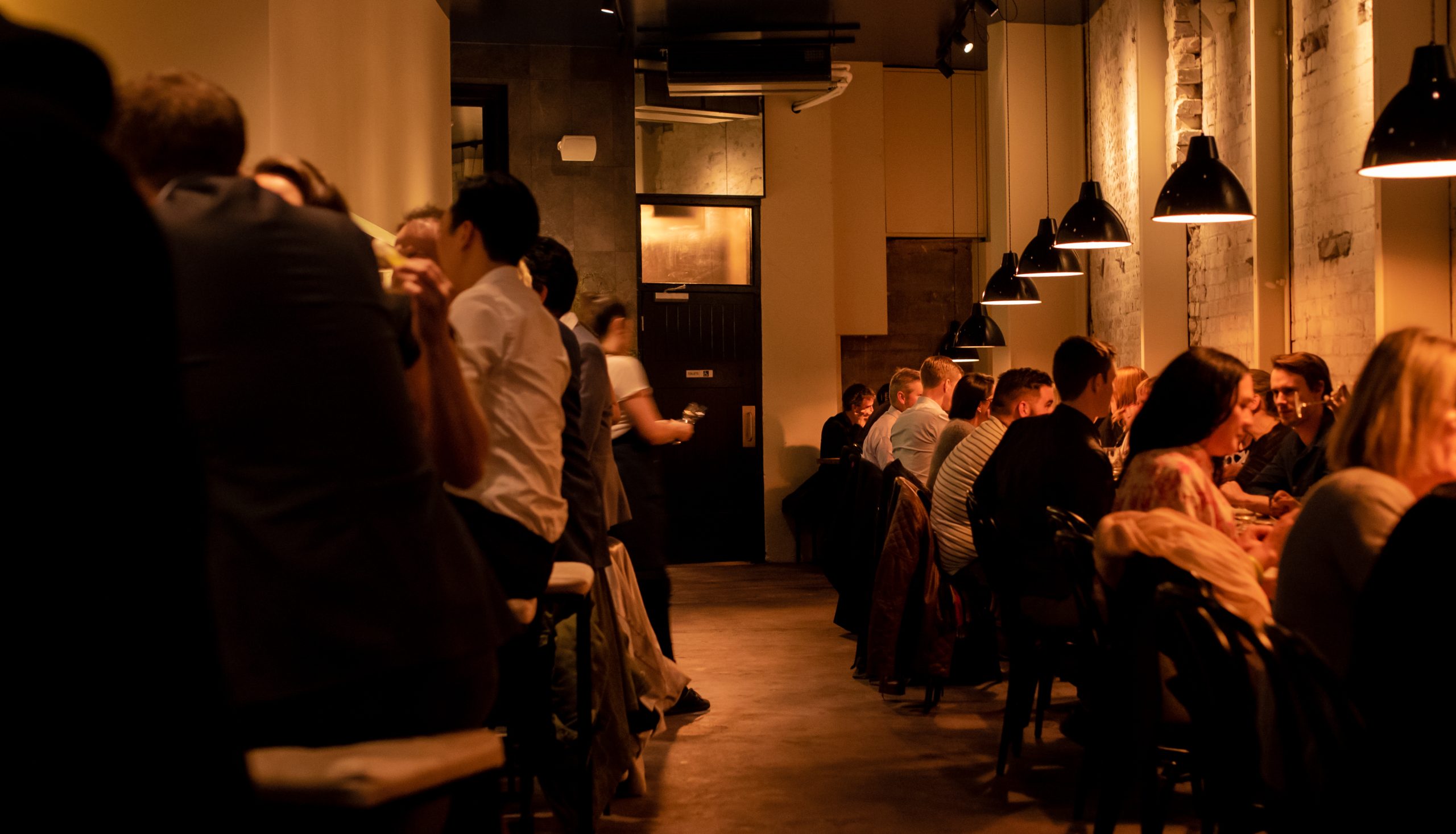 customers sitting on tables with low warm lighting