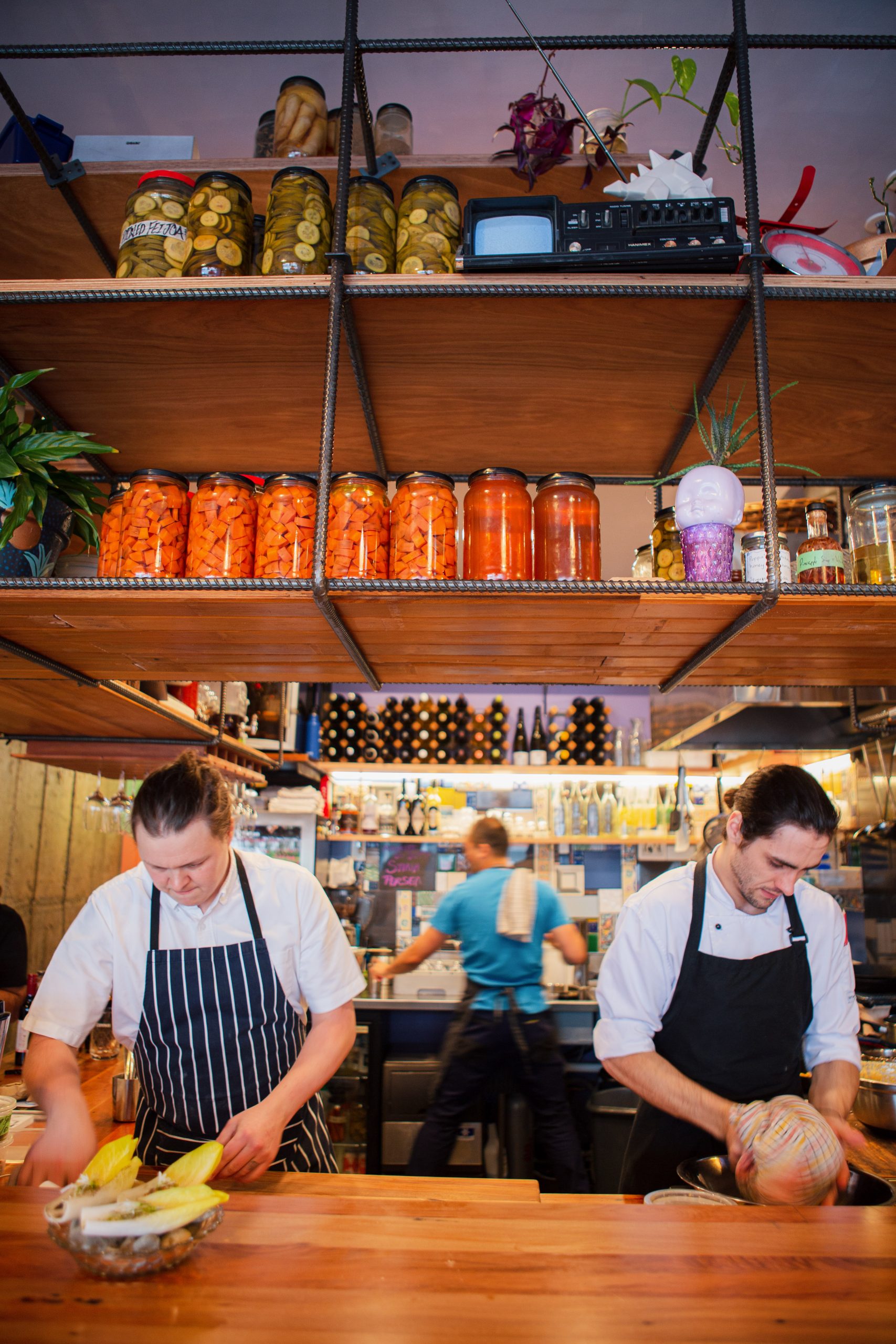 portrait of two male chefs and kitchen hand prepping food