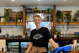 smiling female bartender behind bar bench