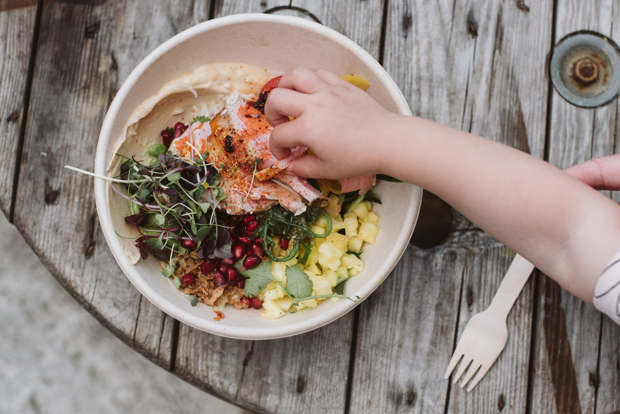 childs hand reaching into a bowl of salmon on table