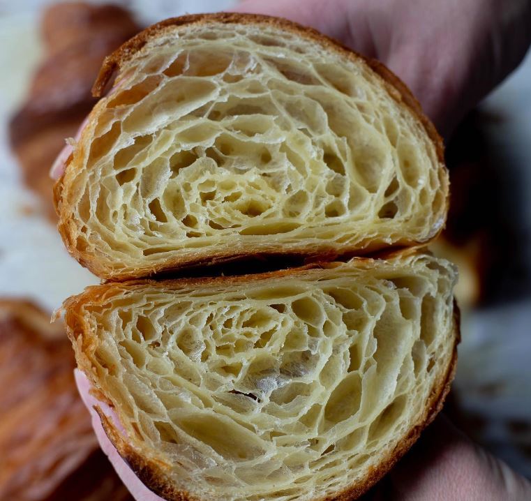 close up of croissant cut in half revealing the layers of the inside