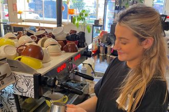 Blonde female steams milk to create coffee